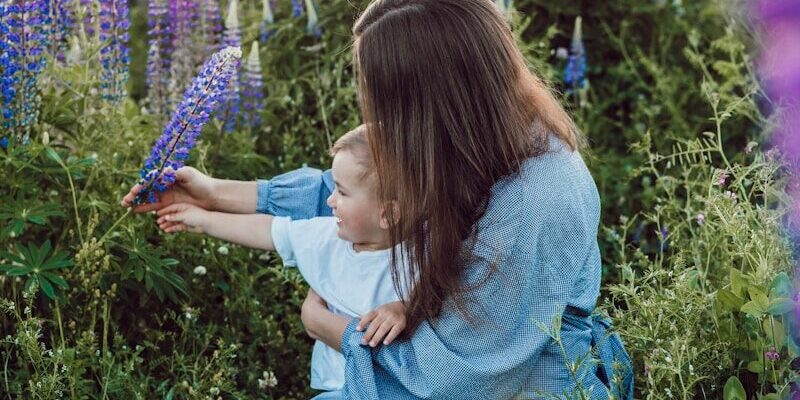 woman sitting with baby on her lap surrounded with purples flower