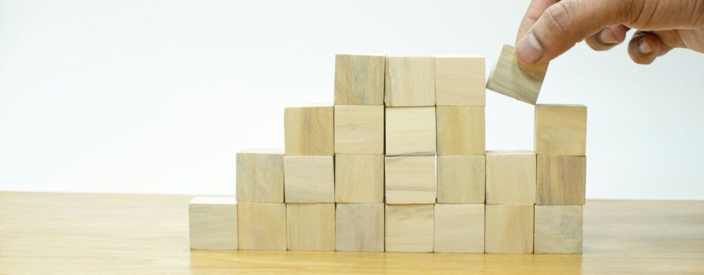 A person placing a block into a pile of wooden blocks