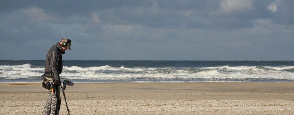 man in black jacket and black pants holding black dslr camera on beach during daytime